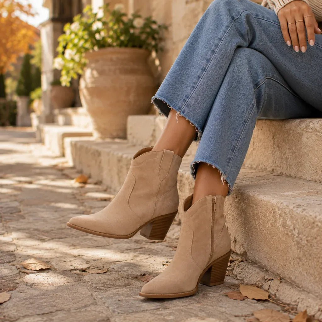 Woman wearing suede ankle booties with cropped denim jeans in an autumn-inspired outdoor setting for the women's boots and booties collection at Solazura Boutique.