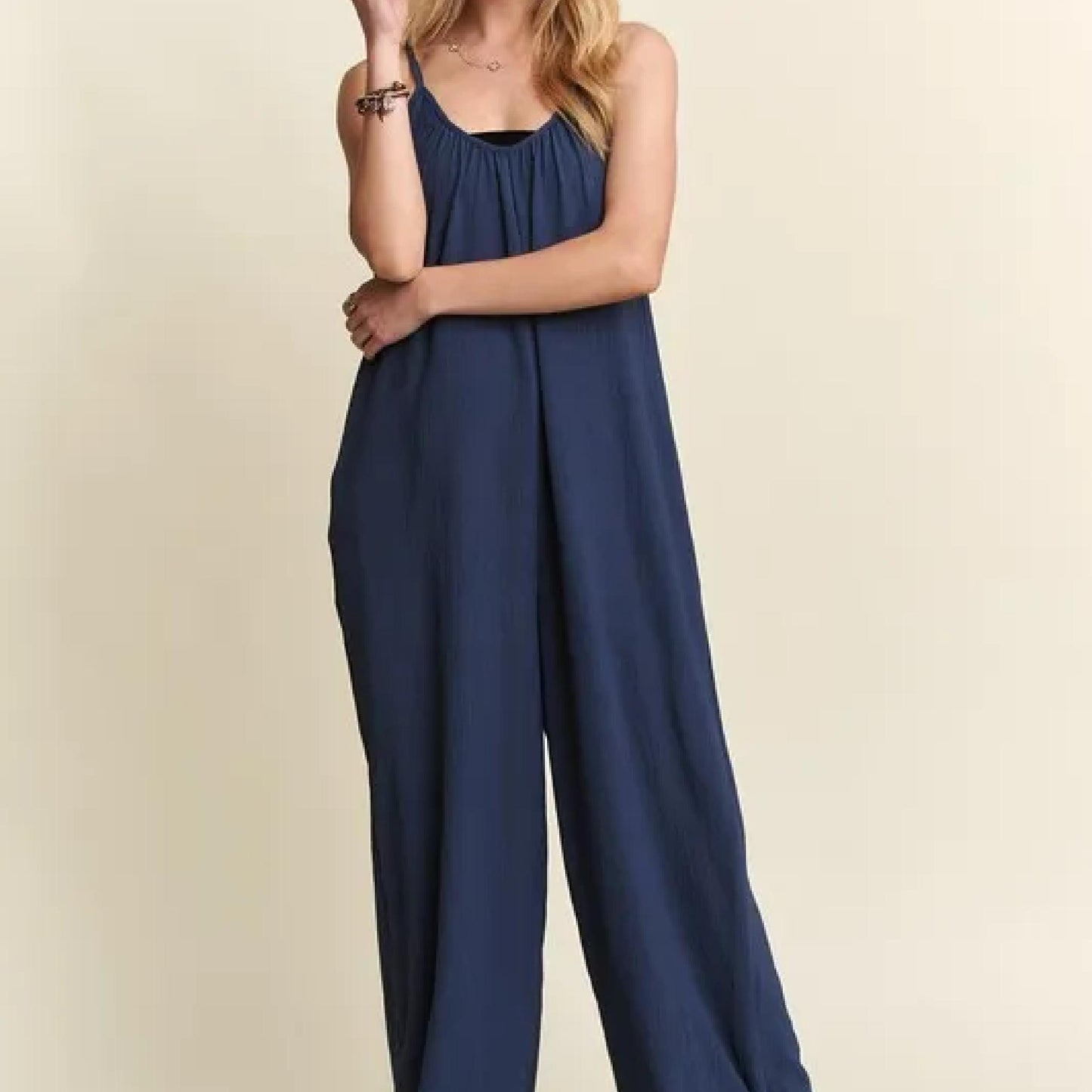 Navy blue jumpsuit worn by a person on a beige background