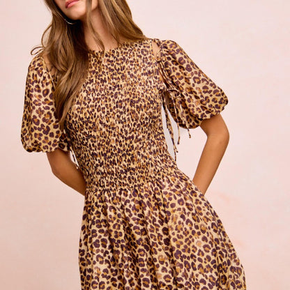 Woman wearing a leopard print dress against a plain background