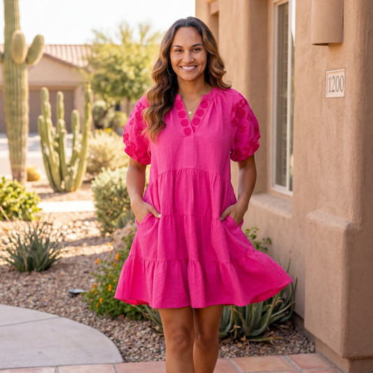Woman in a pink dress standing in front of a house with cacti in the background