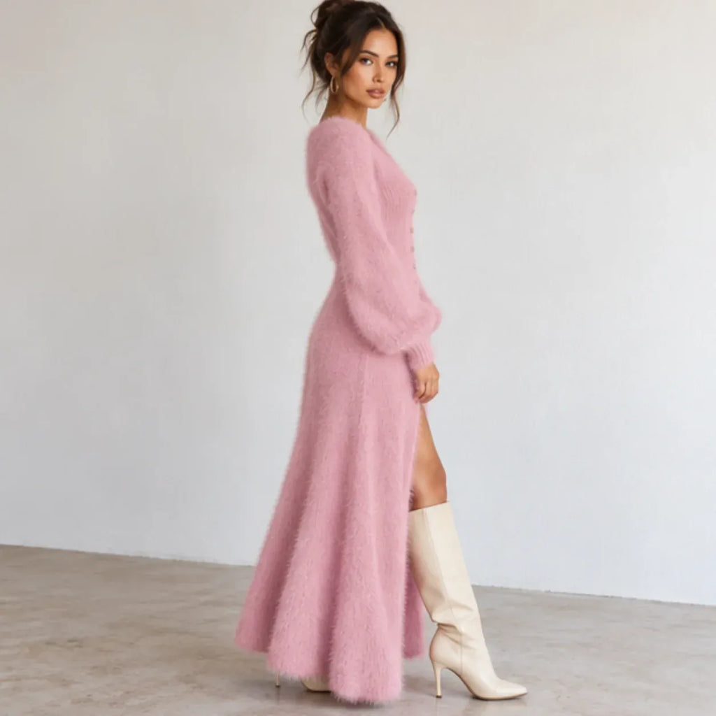 Pink fuzzy knit maxi dress with long sleeves, side button detail, high slit, and white knee-high boots.