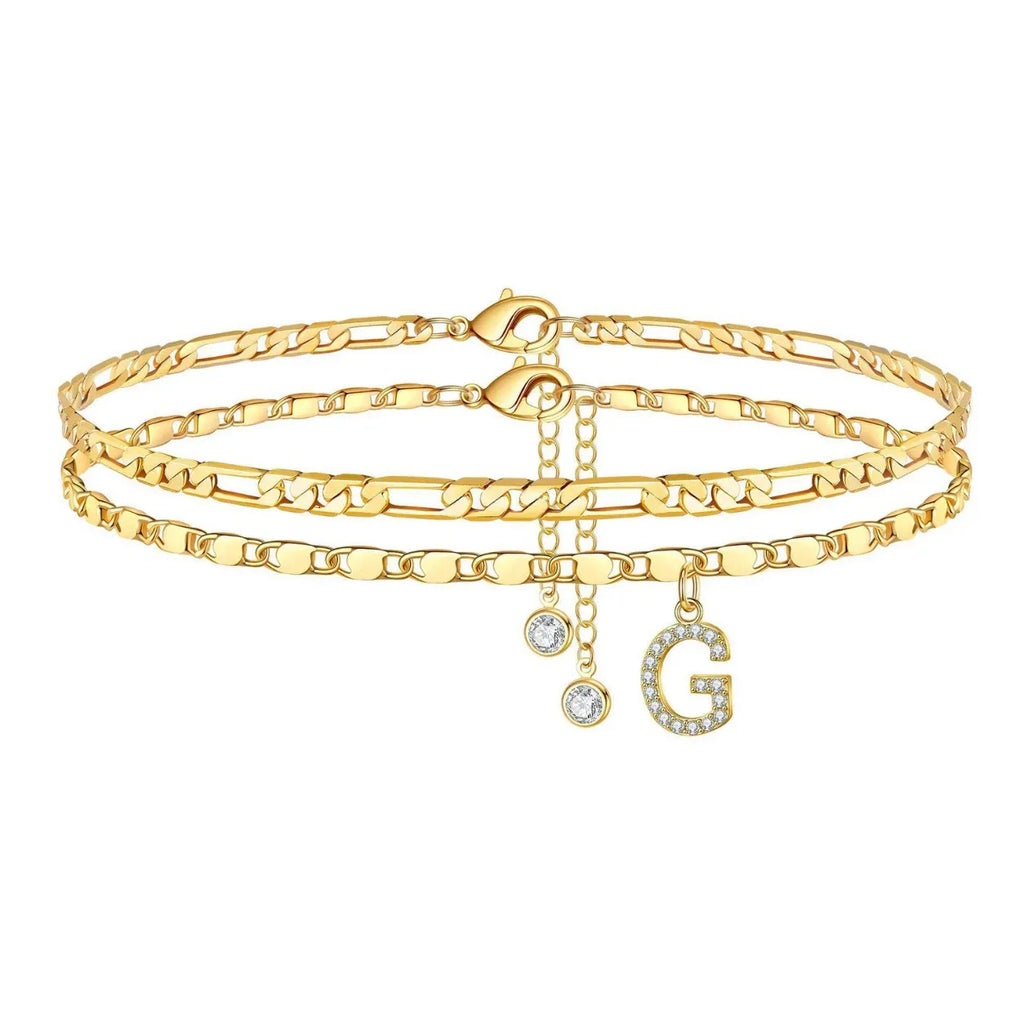 Set of gold anklets with letter 'G' charm on a white background