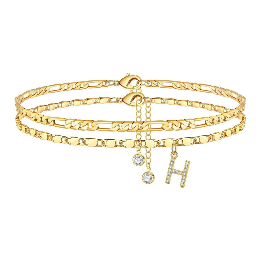Set of gold anklets with letter 'H' charm on a white background