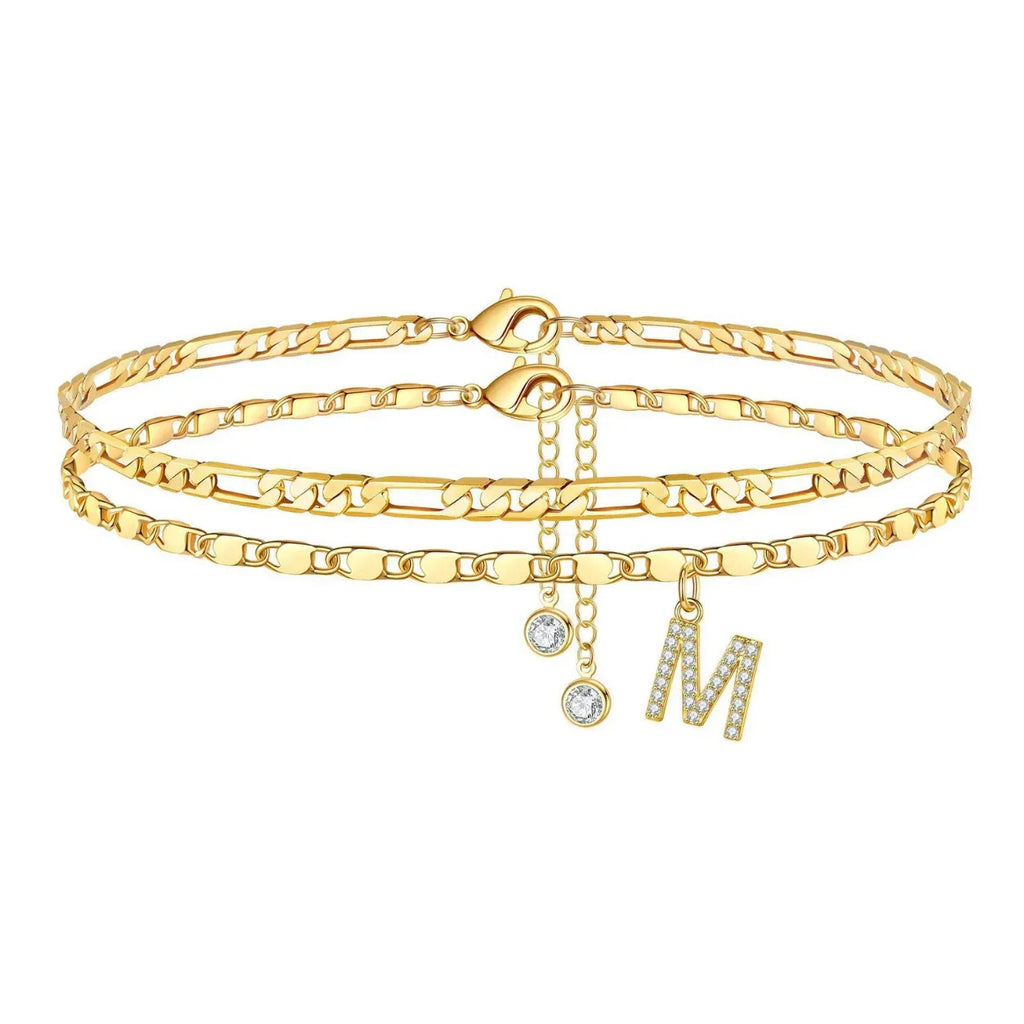 Set of gold anklets with letter 'M' charm on a white background