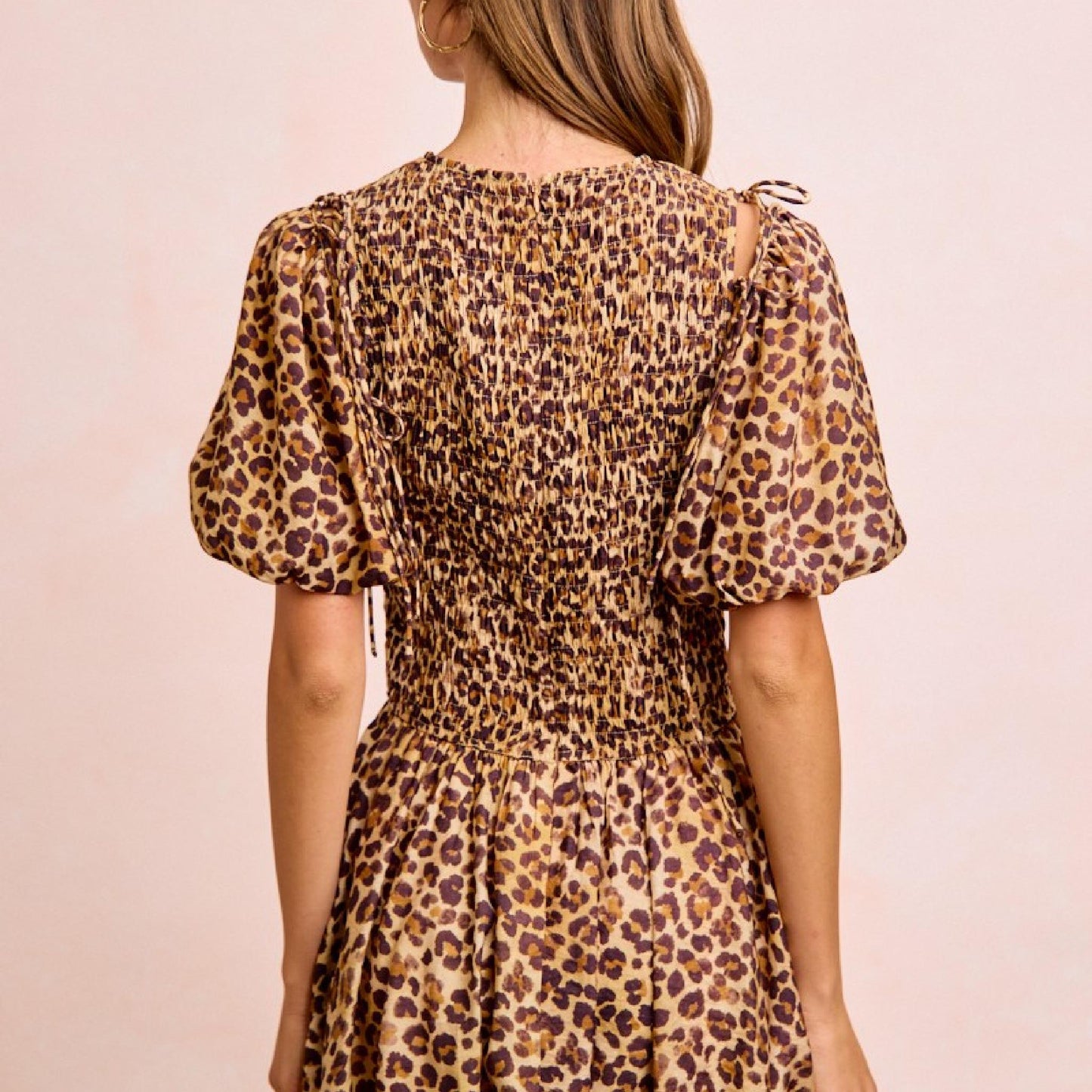 Woman wearing a leopard print dress against a beige background
