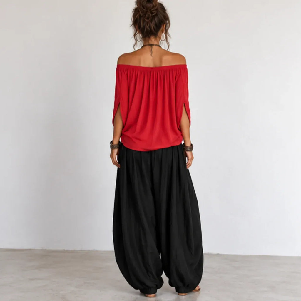 Back view of women’s red and black off-shoulder balloon pants two-piece set with relaxed flowing top