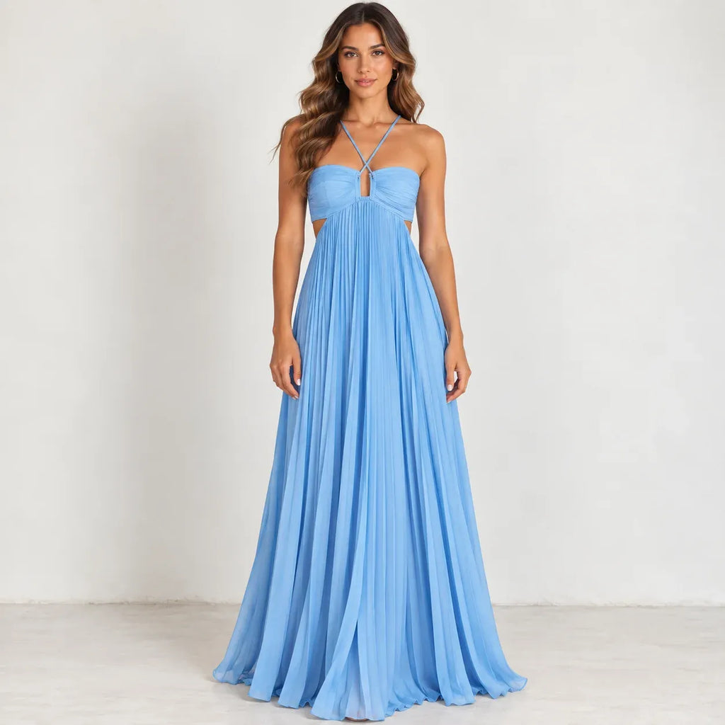 A woman modeling a light blue sleeveless maxi dress with a sweetheart neckline, thin crisscross straps, side cutouts, and a flowing pleated skirt against a plain off-white studio background.