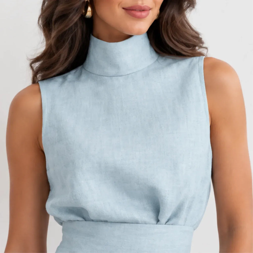 A close-up of a woman wearing a light blue sleeveless mock-neck top or dress bodice, shown against a plain light background.