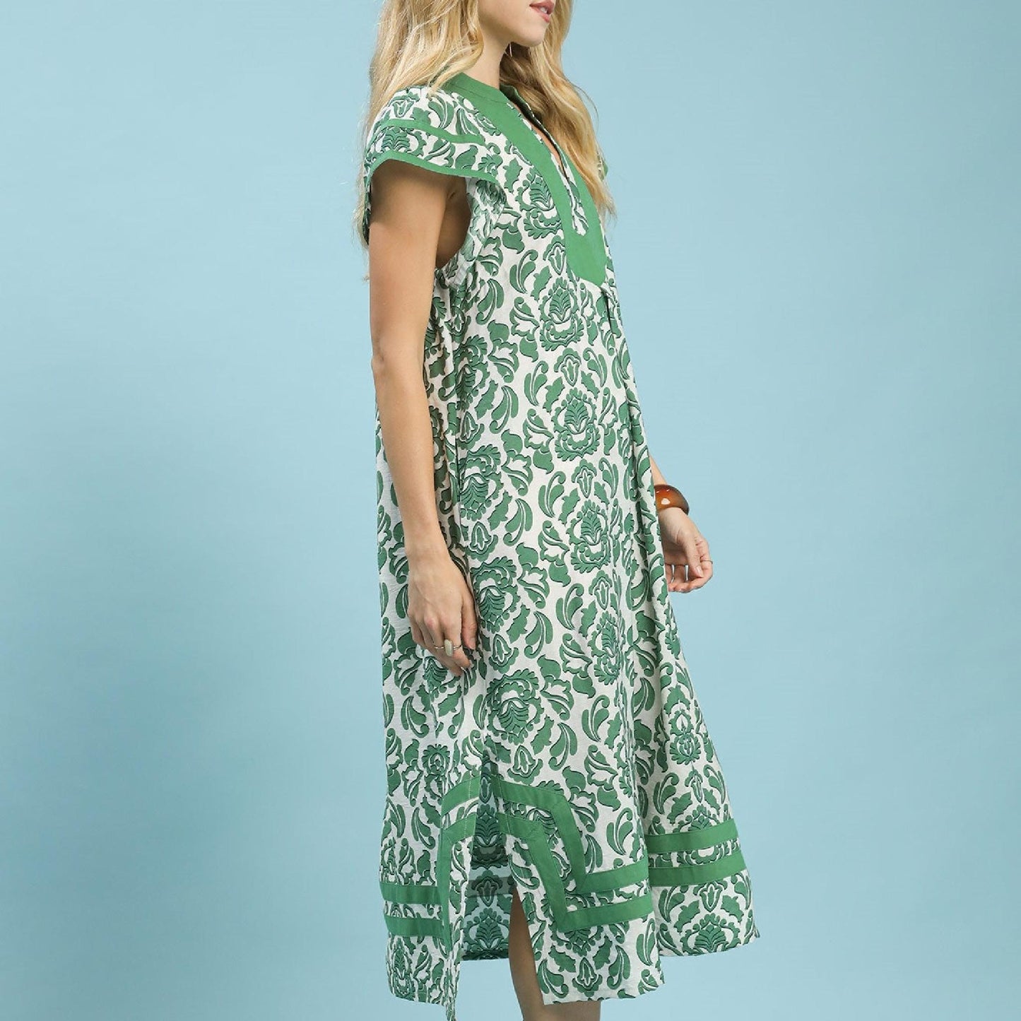 Woman wearing a green and white patterned dress against a light blue background