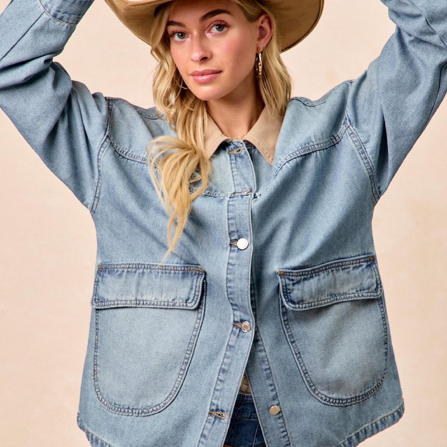Woman wearing a denim jacket and cowboy hat against a beige background