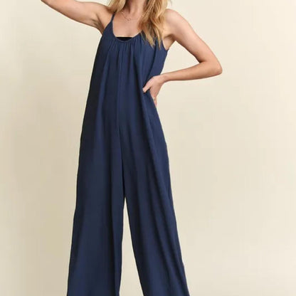 Navy blue jumpsuit worn by a person on a beige background