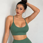 A woman wearing a ribbed sage green sports bra and matching high-waisted leggings, posing against a light gray wall.