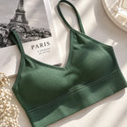 A dark green ribbed sports bra with thin straps, styled on a white surface next to a Paris-themed book, dried flowers, and a decorative tray.