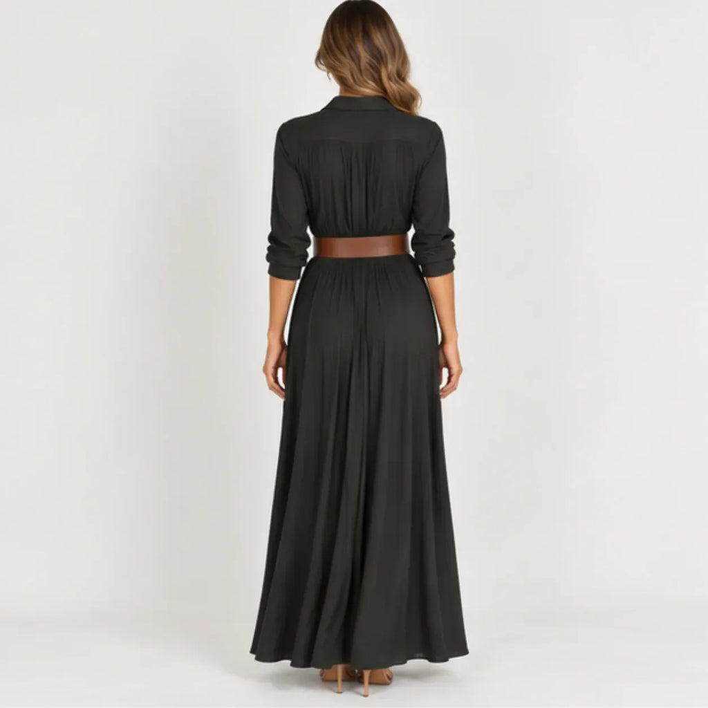 Back view of women’s black belted long sleeve maxi dress with pleated fabric, long flowing skirt, and brown belt