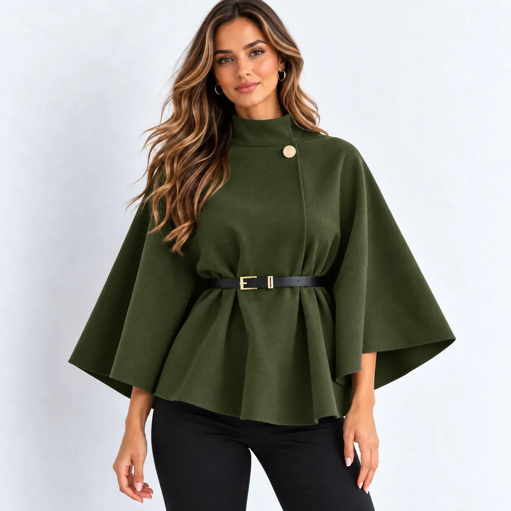 A woman modeling an olive green cape-style top with a single gold button, a matching black belt with a gold buckle, and black pants, set against a plain light gray background.