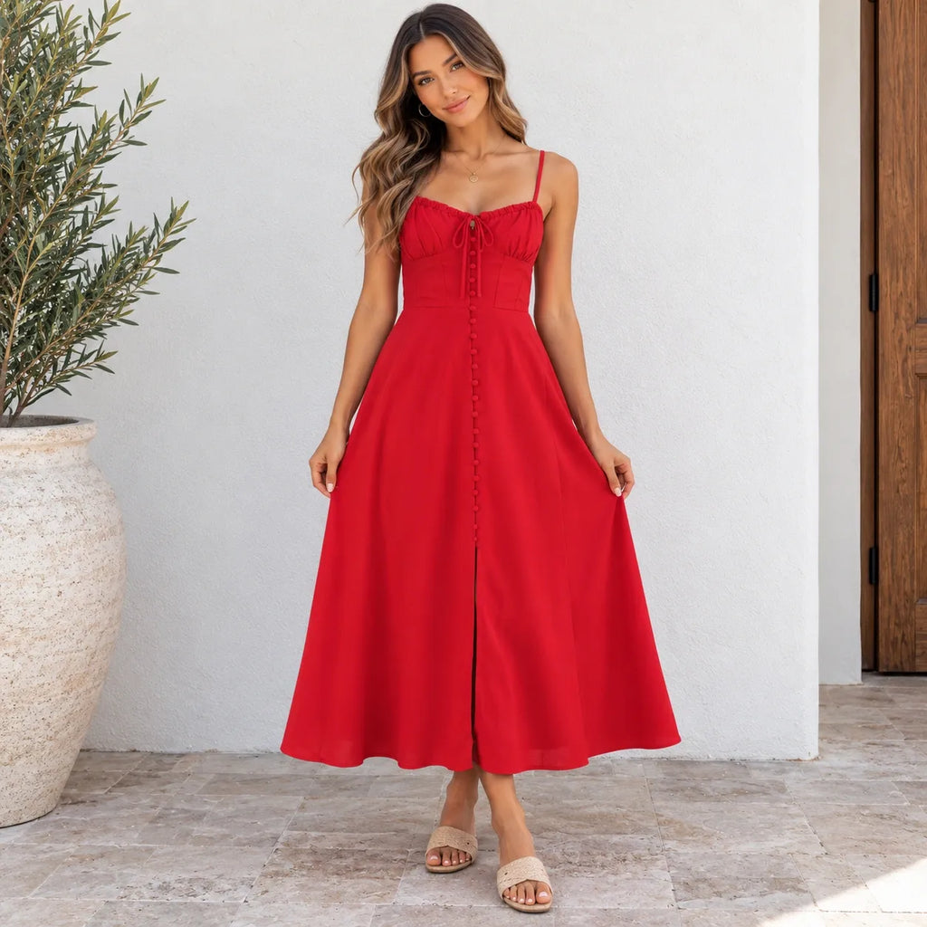 A woman modeling a red midi dress with thin straps, a sweetheart neckline, a front tie detail, and a button-up front, standing against a white wall with a potted plant on the left.