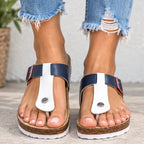 A pair of women's platform thong sandals with navy blue straps, white central panels, and red side accents, shown on a model's feet with frayed blue jeans.
