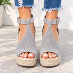 A pair of women's platform wedge sandals with gray perforated mesh uppers and espadrille-style jute soles, shown on a model's feet with frayed blue jeans.