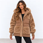 A woman modeling a tan faux fur puffer jacket with a matching faux fur hood, featuring a quilted front panel, ribbed cuffs, and front pockets, set against a plain white studio background.