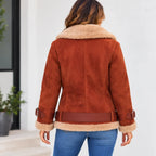 A woman viewed from the back wearing a rust-brown suede shearling jacket with a beige sherpa collar and cuffs, paired with blue jeans.