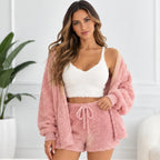 A woman models a cozy two-piece loungewear set consisting of a white fuzzy crop top and a matching pink fuzzy drawstring shorts, styled with a pink fuzzy open-front cardigan.