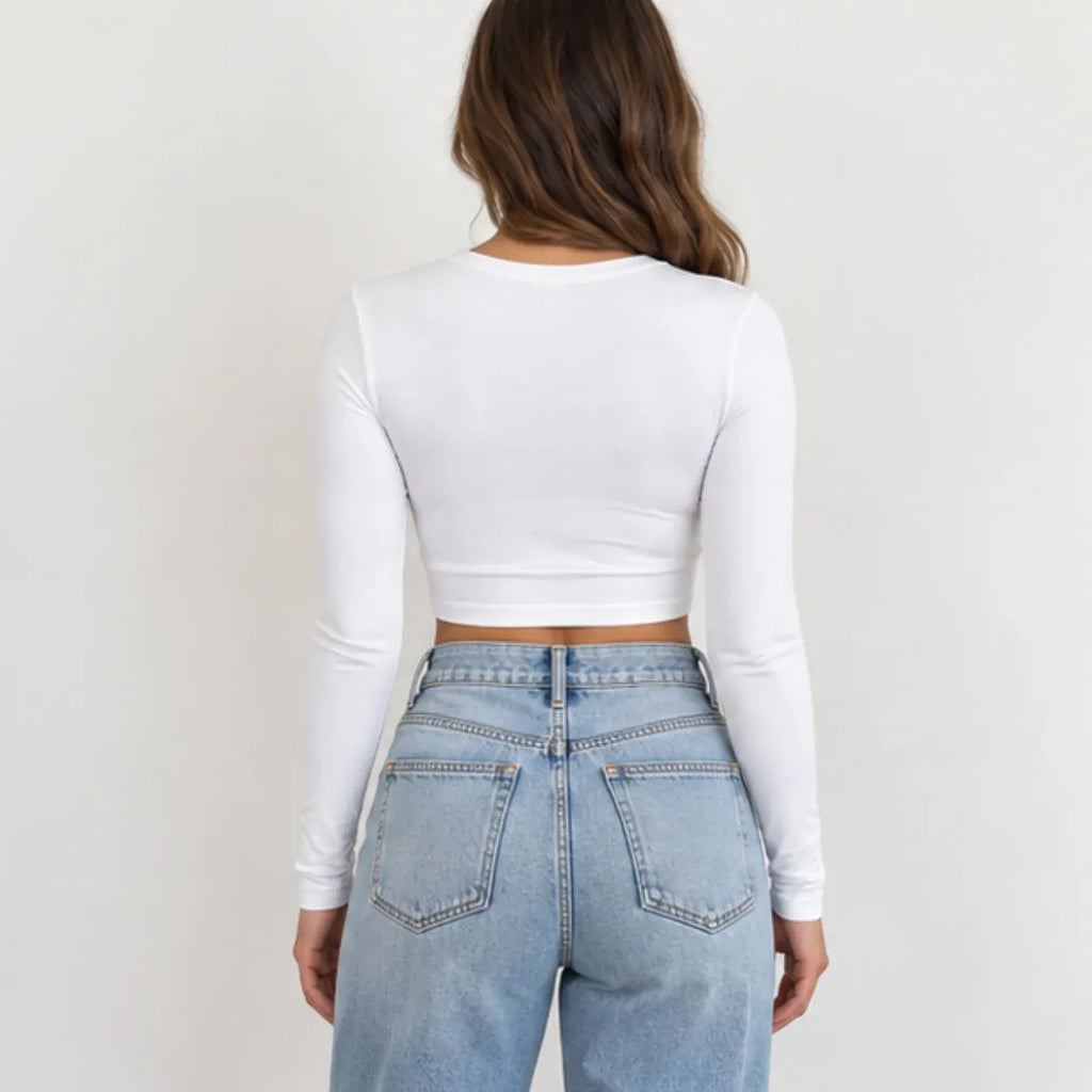 A woman shown from the back wearing a fitted white long-sleeve crop top and light blue jeans against a plain light background.