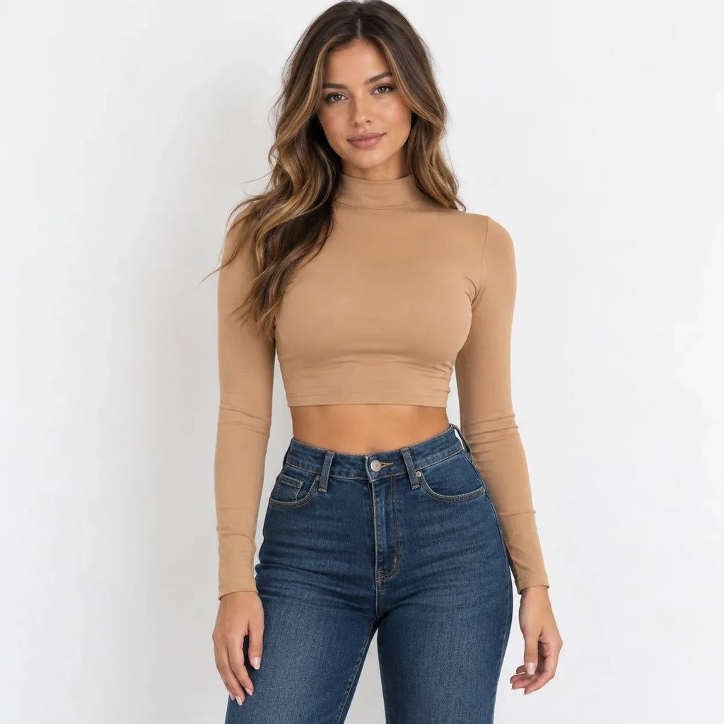 A woman modeling a khaki long-sleeve mock neck crop top paired with light-wash distressed blue jeans against a plain white background.