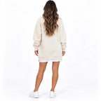 Beige back: Back view of a beige long sleeve sweater dress with cuffed sleeves and a ribbed hem.