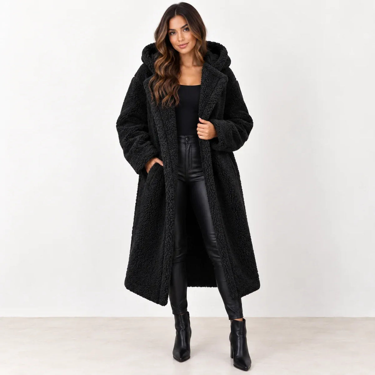 Black: Women's black longline teddy fleece coat with hood and wide lapels, shown from the front.