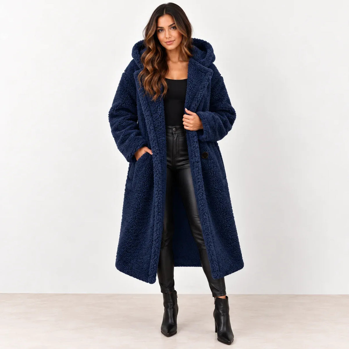 Dark blue: Women's dark blue hooded teddy fleece coat worn open over a black top and pants, front view.