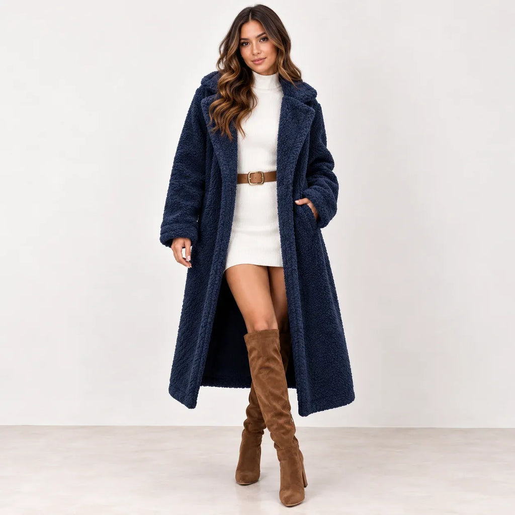 Navy blue: Women's navy blue longline teddy fleece coat styled over a white belted dress with tall brown boots.