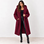 Wine red: Women's wine-red longline teddy fleece coat with hood and front pockets, styled over a black outfit.