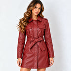 A woman modeling a burgundy faux-leather trench coat with a matching waist tie belt, photographed against a light gray studio background.