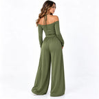 Olive green back: Back view of an olive green wide-leg jumpsuit showing an off-shoulder neckline and neck tie straps.