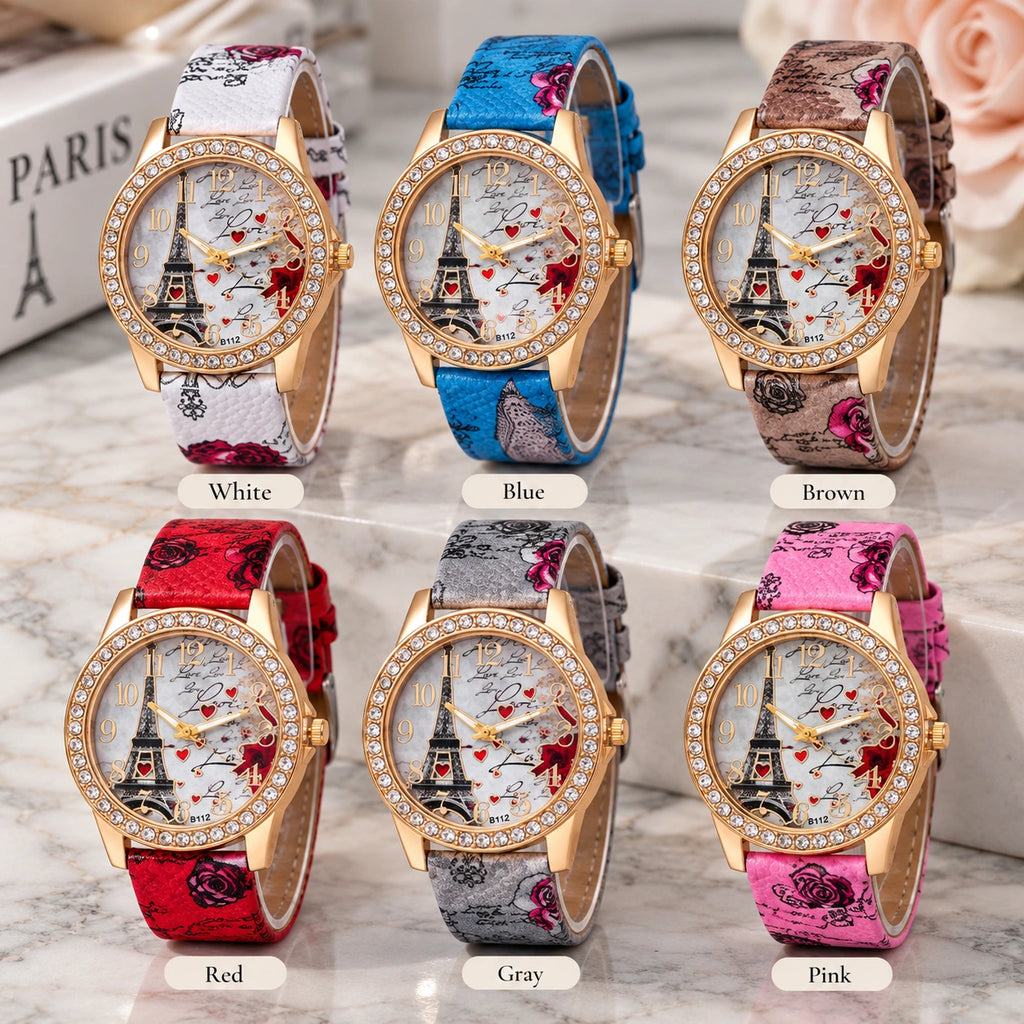 Six women's analog wristwatches with gold-tone cases and crystal-studded bezels, each shown with a different printed strap color: white, blue, brown, red, gray, and pink. The watch faces feature a Paris Tower Eiffel Tower illustration with red heart details.