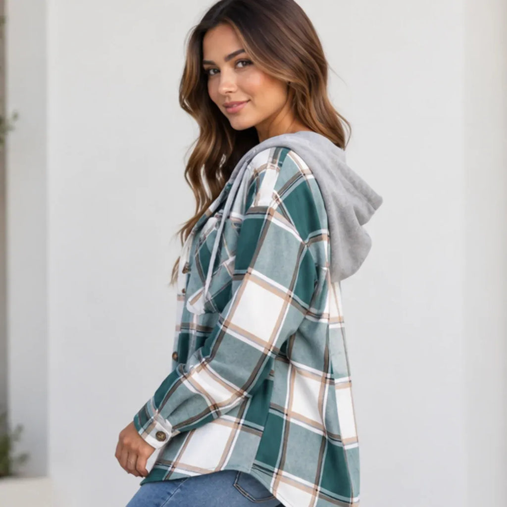 A woman wearing a green and white plaid hooded flannel shirt with a gray hood, paired with blue jeans, photographed against a light gray background.