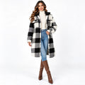 A woman modeling a black and white buffalo plaid faux fur coat with a black collar, styled with a cream turtleneck, blue jeans, and brown knee-high boots against a white studio background.