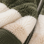 Close-up of a plush sherpa jacket with alternating blocks of olive green and cream fleece, featuring a ribbed knit collar and a silver zipper.