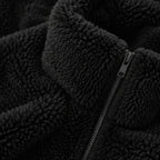 Close-up of a black sherpa fleece jacket with a black metal zipper and a plush collar.