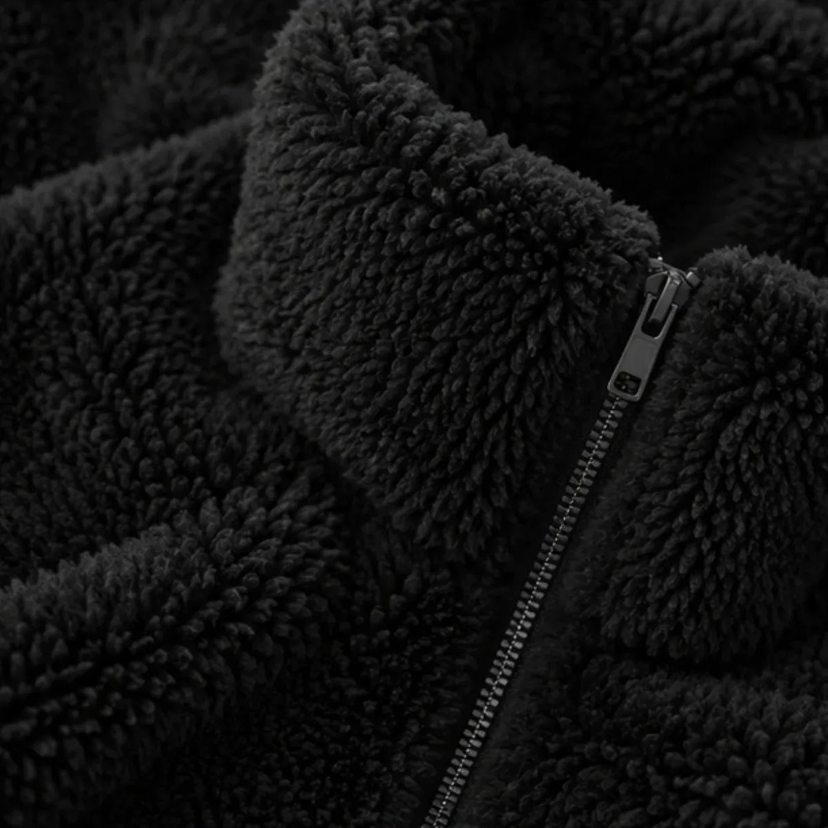 Close-up of a black sherpa fleece jacket with a black metal zipper and a plush collar.
