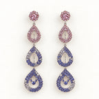 A pair of long teardrop dangle earrings with pink, blue, and purple rhinestone clusters on a white background.