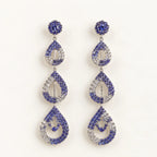 A pair of drop earrings with a silver-tone metal setting, featuring blue and clear rhinestones in a stacked teardrop design on a plain white background.