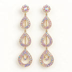 A pair of gold-tone dangle earrings adorned with iridescent, multi-colored rhinestones in a teardrop and floral design, set against a plain white background.