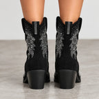 Black suede cowboy boots with silver rhinestone embroidery on the shafts, shown from the back on a model's feet against a neutral gray background.