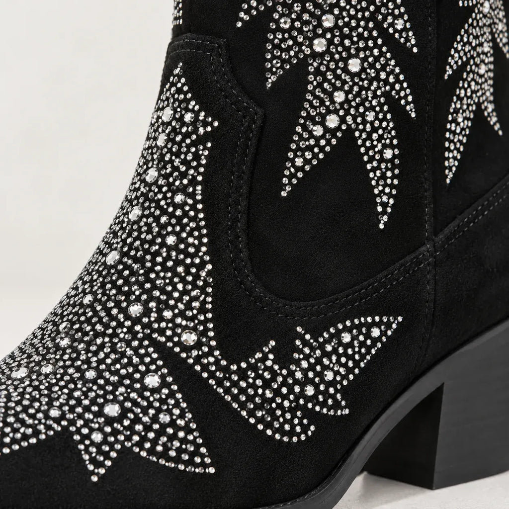 Black suede cowboy boot embellished with silver rhinestone western star patterns, shown on a light gray background.