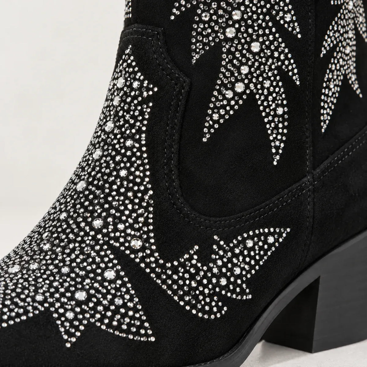 Black suede cowboy boot embellished with silver rhinestone western star patterns, shown on a light gray background.