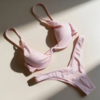 A flat layout of a  pink two-piece bikini against a clean white wall.