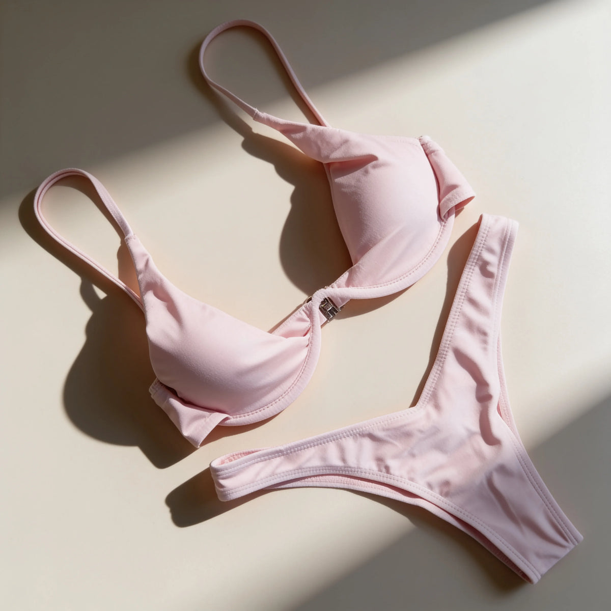 A flat layout of a  pink two-piece bikini against a clean white wall.