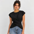 A woman wearing a black short-sleeve top with a twisted wrap-front detail and light blue jeans, photographed against a plain light gray studio background.
