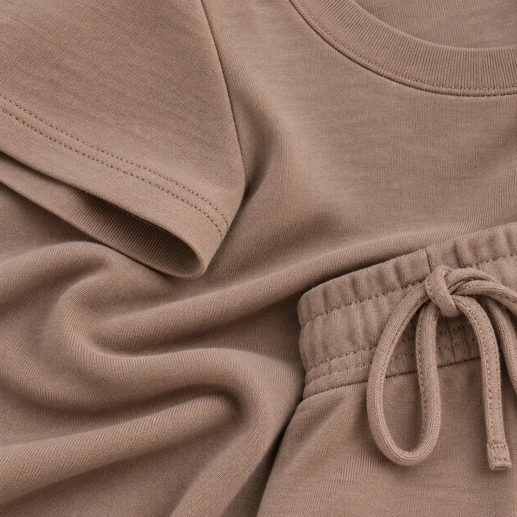 Close-up of a taupe-colored knit loungewear set, showing the texture of a short-sleeve top and matching drawstring shorts.
